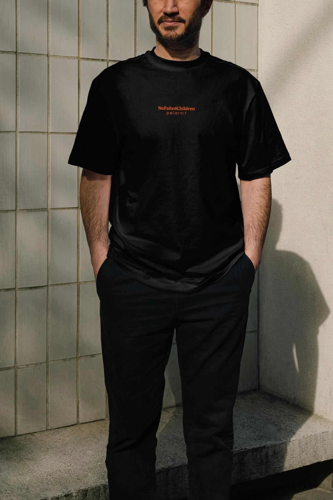 Black oversized T-shirt, front view on model, small orange 'NoFailedChildren x Polaroit' chest print